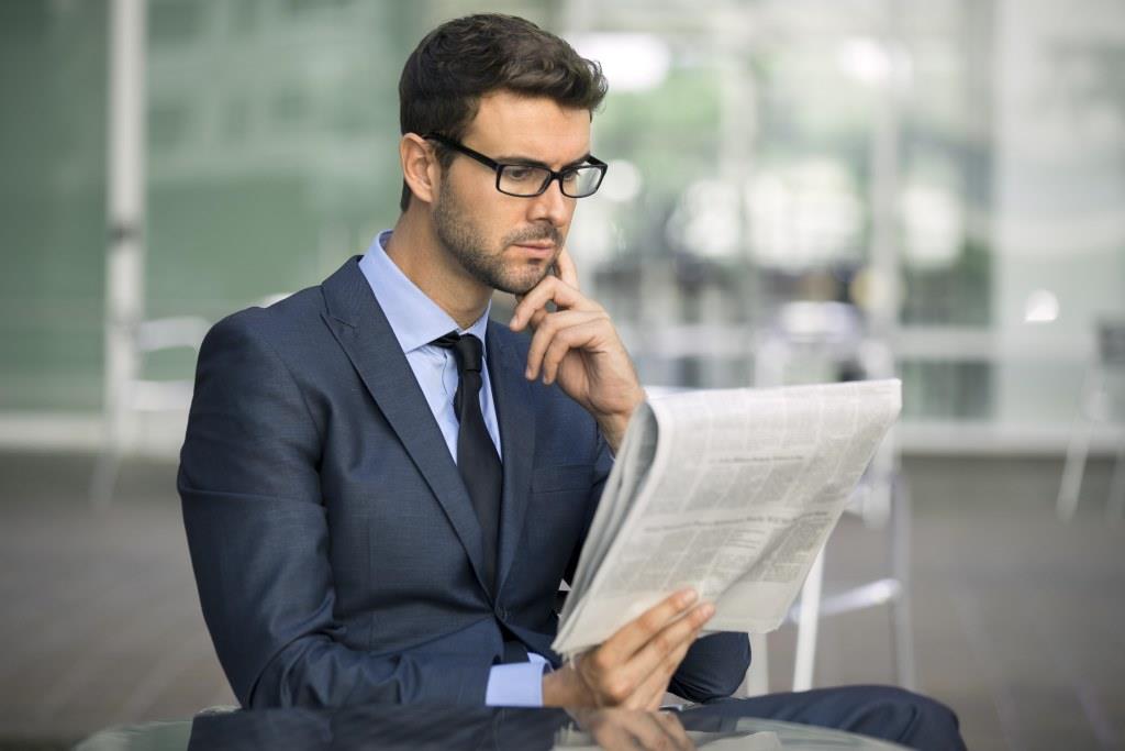 Focused businessman with glasses reading newspaper